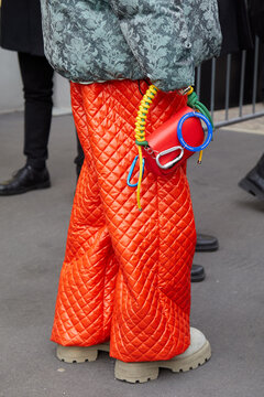 Man with red Alexandre Pavao bag and K-Way orange quilted trousers on January 14, 2024 in Milan, Italy