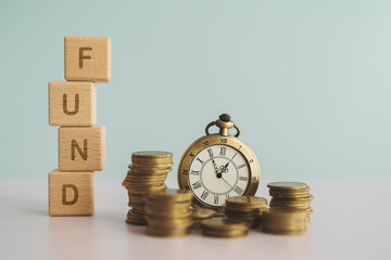 FUND text on stack of wooden cube block with blurred coins and vintage clock for business investment , strategy concept