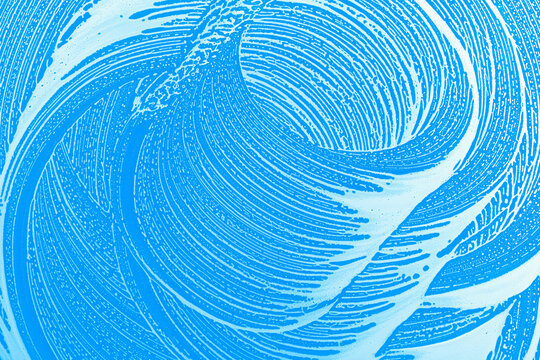 abstract blue background with soap foam waves wiped  on clear glass, blue background