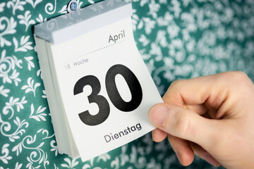 Hand reisst 30. April Zettel vom Kalender