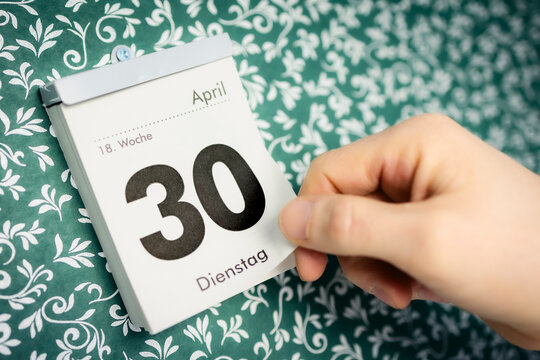 Hand reisst 30. April Zettel vom Kalender
