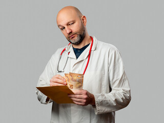 Doctor holding a envelope and counting pile of cash looking suspiciously at the viewer. Bribery or...