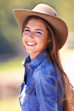 Happy woman, portrait and cowgirl with hat on farmland for adventure, travel or outdoor journey in Texas. Female person with smile in western fashion, denim shirt and cap at ranch in the countryside