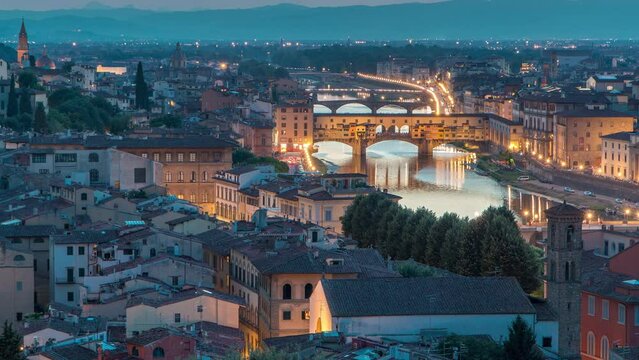 Skyline aerial view of Arno River day to night transition timelapse, Ponte Vecchio from Piazzale Michelangelo after sunset, Florence, Italy. Colorful sky. Evening mist covered illuminated buildings
