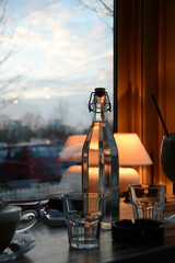 Cafe atmosphere at golden hour. Water glass bottle.