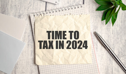 Crumpled paper with TIME TO TAX IN 2024 text on clipboard. Business concept with pen and green...
