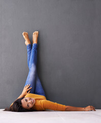 Woman, smile and wall background, trendy, clothes on wall and relaxing on floor in portrait with...