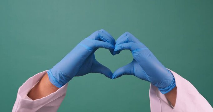 Close up of two hands forming heart shape, surgical gloves doctor medicine