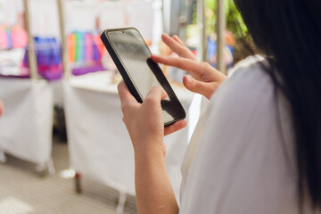 Unrecognizable young woman outdoors using phone touching screen with finger, copy space.