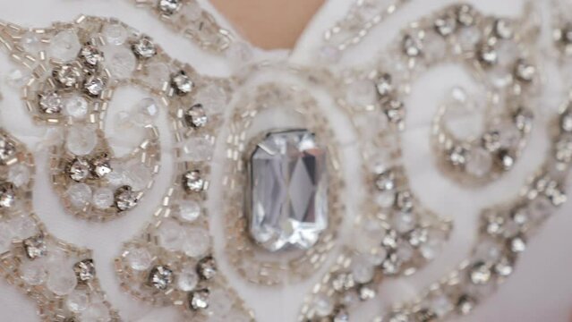 A close-up of the bride's dress decorated with stones, a luxurious wedding dress. Wedding fashion.