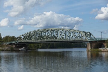 Old metal railway bridge over lake Vanajavesi against sky with clouds in summer, Hämeenlinna, Finland.