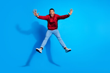 Fototapeta na wymiar Full length photo of impressed young person raise hands jump fall empty space ad isolated on blue color background