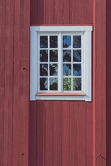 Window with white frame on a old red wooden building.
