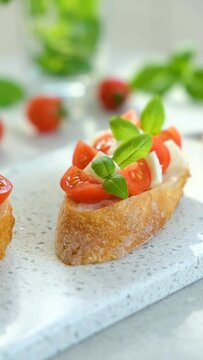 Bruschetta with cherry tomatoes, mozzarella cheese and basil in sun rays on marble board. Traditional Italian appetizer, snack or antipasto. Vegetarian food. Healthy eating. Mediterranean food.