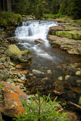 Mountain stream with colorful autumn leaves flowing over rocks and rocks.