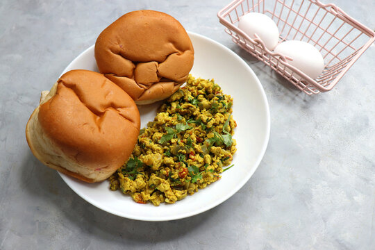 Anda Masala Bhurji or Spicy Indian scrambled eggs with bread or Bun Pav, a popular street food in Mumbai. Served in a white plate along with copy space. egg bhurji or parasi akuri. with jowar bhakri.