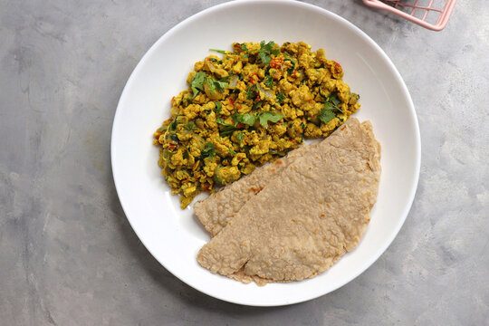 Anda Masala Bhurji or Spicy Indian scrambled eggs with bread or Bun Pav, a popular street food in Mumbai. Served in a white plate along with copy space. egg bhurji or parasi akuri. with jowar bhakri.