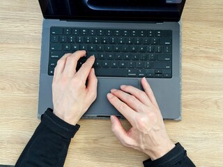 Hands using Macbook on wooden table top view 