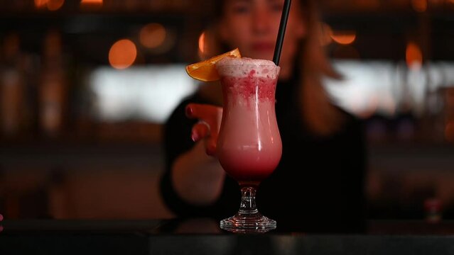 Bartender woman serves Cocktail into a transparent glass