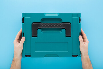 Man hands holding and showing new dark black green professional plastic toolbox for repair tools,...