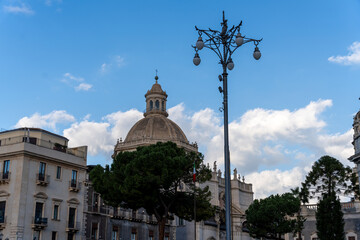Fototapeta na wymiar A tall building with a dome on top stands in front of a street light