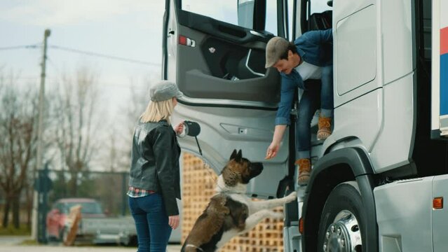 A woman with a dog welcomes and hugs her truck driver husband who has just returned from the trip.