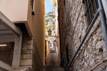 A narrow alleyway with a stone wall and a lamp hanging from the ceiling