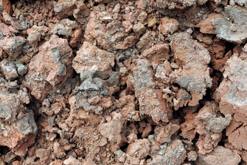 Lumps of brown earth in the field after harvesting. The texture of clumps of clay soil. Plowed land in close-up.