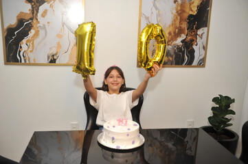 Menina comemora aniversário de dez anos em casa, festa doméstica com bolo e balões com numero 10...
