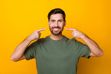 Photo of cheerful positive man wear khaki t-shirt showing two fingers white teeth isolated yellow...