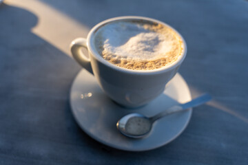 A white coffee cup with a spoon on top of it