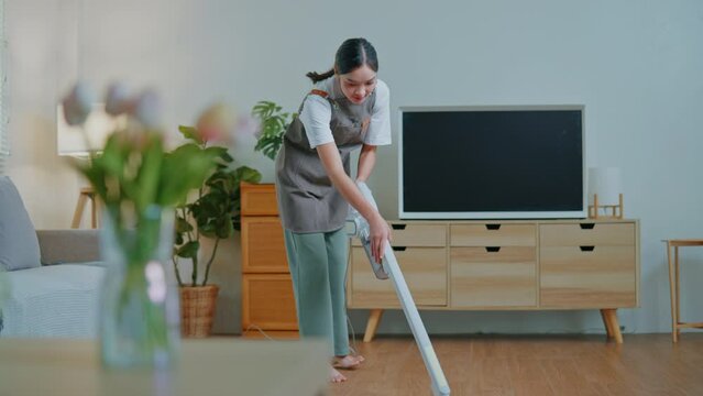 Female housekeeper is cleaning mop the floor and vacuum dust on floor by vacuum cleaner in living room and bedroom.