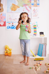 Kid, toy and blowing bubbles for childhood development, playing and having fun alone in room. Happy, growth and face of young girl in kindergarten for learning, soap bubble wand and activity games