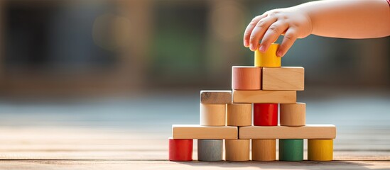 Child's Hand Engaging in Interactive Play by Adding Colorful Block to Tower