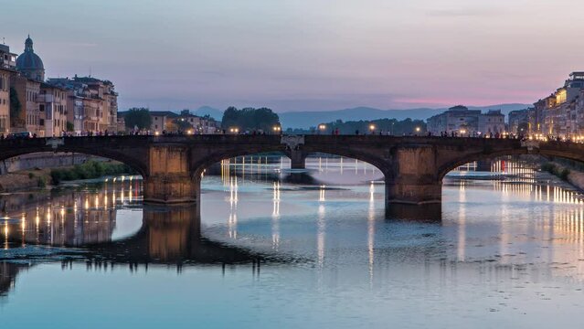 Twilight scene of Ponte Santa Trinita (Holy Trinity Bridge) day to night transition timelapse over River Arno with reflections on water after sunset. Florence, Tuscany, Italy