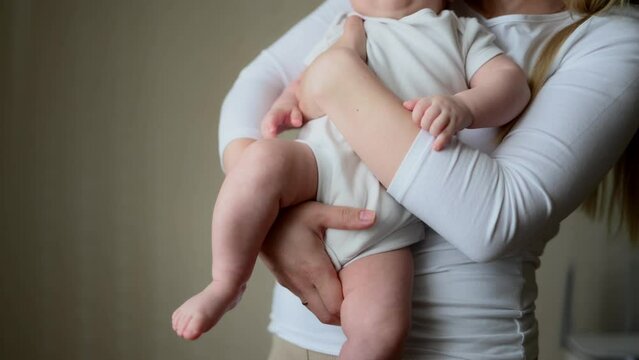  Mother holds and hugs her baby, close-up. Concept of motherhood, maternity leave, child care, nanny