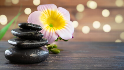 Basalt stones for massage and flower on a dark wooden table. selective focus, bokeh, copy space