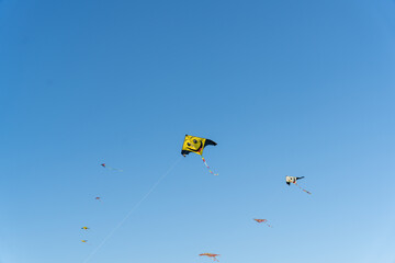 A yellow kite with a smiley face flies in the sky