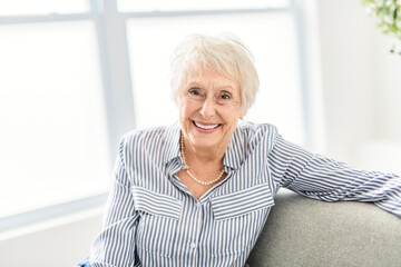 Fototapeta na wymiar Smiling mature grey senior woman looking at camera