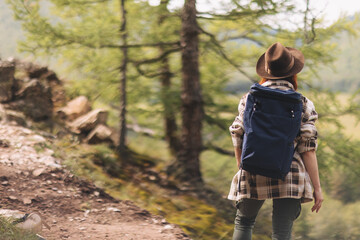 A young woman walks along a path in the forest in the mountains in a fleece shirt and with a blue...