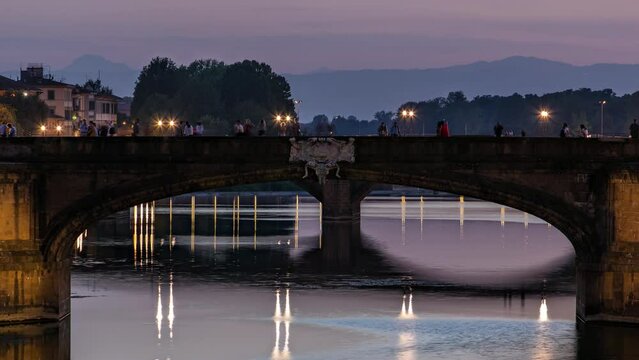 Twilight scene of Ponte Santa Trinita (Holy Trinity Bridge) day to night transition timelapse over River Arno with reflections on water after sunset. Close up view. Florence, Tuscany, Italy