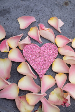 pink and light flowers on concrete background as voucher or card background with pink chocolate heart with sugar pearls