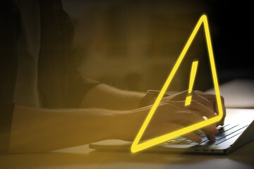 person working on a laptop computer, yellow warning triangle as an alert of spam or malware hovering in front, safety, danger, network, cybersecurity