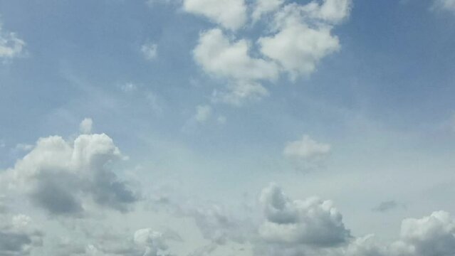 Bright white clouds fly across the bright blue sky. The sky is clear in the afternoon. Background view of clouds moving in the wind. Copy space