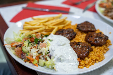 Fototapeta premium A plate of food with a salad, meat, and fries