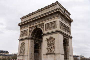 The Arc de Triomphe is a large, white arch with intricate carvings and statues