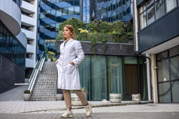 Smiling female surgeon standing outdoors while looking away. A female healthcare worker leaving the house in her uniform.