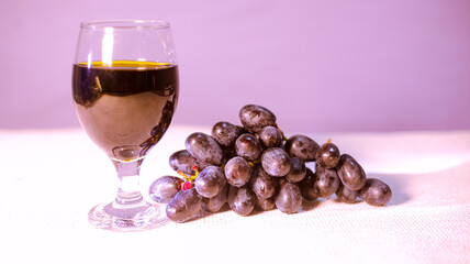 Glass of tasty dark red wine and bunch of black grapes.
