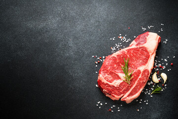 Beef steak. Ribeye steak raw meat on black. Top view with copy space.