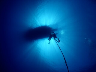 scuba divers going back to boat ascending by rope underwater blue water